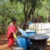 Jennifers mor henter vand i tanken foran huset. Hun har en rød manta på. Det er en af wayuu-folkets dragter. Foto: Genesis Gutierrez.