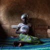 Fatoumata på sengen, hvor hun sover. Læg mærke til papstykkerne langs væggen. De hjælper med til at holde fugten ude. Foto: William Vest-Lillesøe