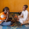 Hamidou og Abdullah har ingen møbler i deres værelse. De sidder på måtter på gulvet. Det er også her de sover. Men der er elektricitet i huset, så de kan nemt få opladet deres telefoner. Foto: William Vest-Lillesøe