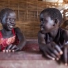Rhoda og hendes gode veninde, som også hedder Rhoda. De sidder på bænken i et klasselokale på deres skole, St. Andrea Primary School - foto: William Vest-Lillesøe